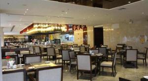 a dining room with tables and chairs in a restaurant at Golden Phoenix International Hotel in Xiahuangtang