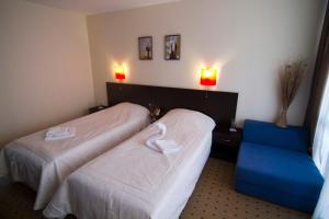 a hotel room with two beds and a blue chair at Tropics Hotel - Ultra All Inclusive in Sveti Vlas +55 photos