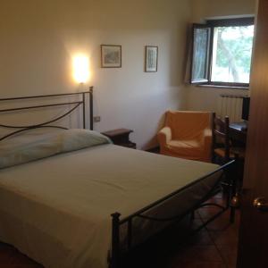 アメリアにあるAgriturismo Collepinaのベッドルーム1室(ベッド1台、椅子、窓付)