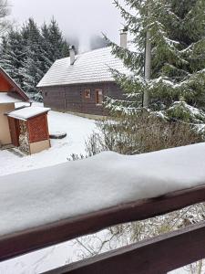 una recinzione innevata di fronte a una cabina di Cozy cottage in the heart of Čičmany a Čičmany
