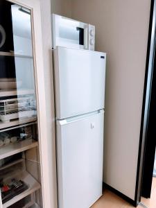 einen weißen Kühlschrank in einer Küche neben einer Tür in der Unterkunft Hotel Small World in Hiroshima