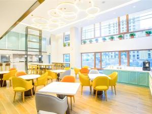 a restaurant with tables and chairs and windows at Magnotel Harbin Songbei Wanda Wenlvcheng in Harbin