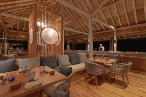 a restaurant with wooden tables and chairs and a clock at Six Senses Laamu in Laamu