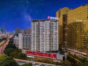a tall white building in a city at night at Echarm Hotel Nanning the MixC Exhibition Center Metro Station in Nanning