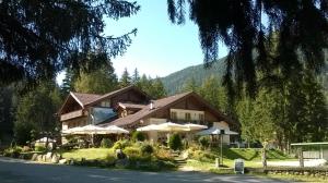 une maison dans les montagnes avec un arbre dans l'établissement Baita Velon, à Vermiglio