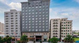 un grand bâtiment avec deux grands bâtiments et des palmiers dans l'établissement Xana Hotelle· Dongguang Chang'An Binhaiwan Jian'An Road, à Hongmei