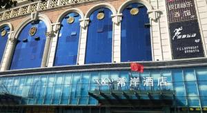 un bâtiment avec des fenêtres bleues portant des inscriptions chinoises dans l'établissement Xana Hotelle Yining Airport Road Jinwuyuan, à Yining Airport