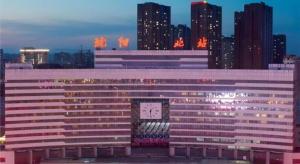 a large building with a clock on it in front of a city at Echarm Hotel Shenyang Zhongjie North Station Metro Station in Shenyang