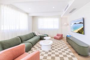 芬加尔湾Ornos, 1-14 Market St - ducted air con, cot, highchair, Linen and Bed Making的客厅配有绿色沙发和椅子