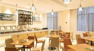 a restaurant with wooden tables and chairs and windows at City Comfort Inn Tonglu Fuchun River Qiaolin Road in Tonglu