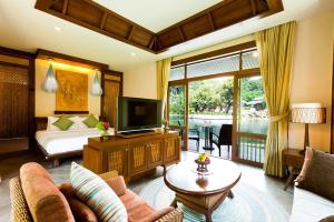 sala de estar con TV, sofá y cama en Sibsan Resort & Spa Maetaeng Chiang Mai, en Mae Taeng
