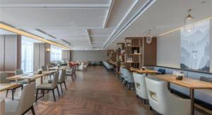 a dining room with wooden tables and white chairs at Echeng Hotel Nanning Huqiu Metro Station in Nanning