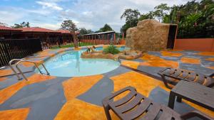 a swimming pool with two chairs and a rock at Rústicas Dani & Fam in Fortuna