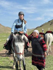une femme à cheval à côté d'une autre femme dans l'établissement Yurt camp Asman at Song Kol lake, à Akchiy