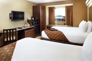 a hotel room with two beds and a flat screen tv at Microtel Inn & Suites by Wyndham Wheeling at The Highlands in Triadelphia