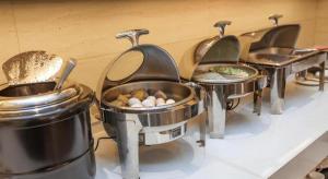 a row of buffet tables with pans and food at Borrman Hotel Yongzhou High Speed Railway Station in Guzhuting