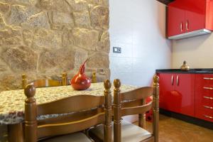 cocina con armarios rojos y pared de piedra en Casa Carla, en Palas de Rei 