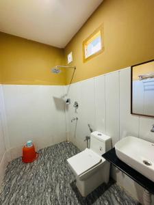 a bathroom with a white toilet and a sink at Kaziranga Tea Nest Homestay in Kāziranga