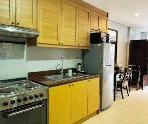 Una cocina con gabinetes de madera y un refrigerador de acero inoxidable. en Crosswinds Standard Suite, en Ulot