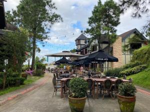 una cafetería al aire libre con mesas, sillas y sombrillas en Crosswinds Standard Suite, en Ulot