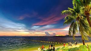 a group of people on a beach at sunset at Downtown Oasis 芭提雅市中心独栋泳池别墅 A 5卧6卫 KTV BBQ 芭提雅海滩步行街500m in Pattaya South