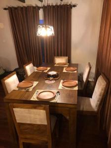 einen Esstisch mit Stühlen und einen Holztisch mit Tellern in der Unterkunft Tidenest Cottage in Nuwara Eliya