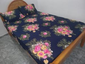 Una cama con un edredón azul con flores. en BG Guest House Jaffna, en Tirunelveli East