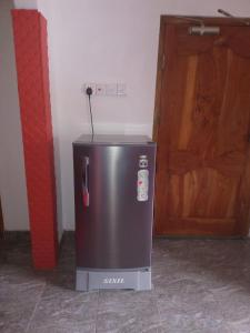 Un pequeño refrigerador en una habitación con puerta de madera. en BG Guest House Jaffna, en Tirunelveli East