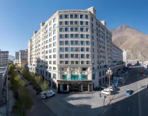 a large white building on a city street with a mountain at City Comfort Inn Shannan Passenger Terminal in Nedong