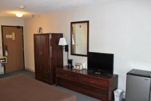 ein Hotelzimmer mit einem Bett und einem TV auf einer Kommode in der Unterkunft Eastwood Inn in Motley