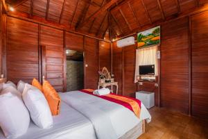 a bedroom with a large bed with wooden walls at The Aura Penida Hills By Bali Cabin in Nusa Penida