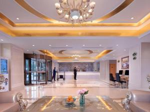 a lobby with a chandelier and a man standing in the background at Vienna Hotel Jinan Railway Station in Jinan
