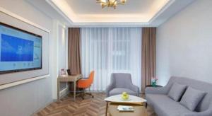 a living room with a couch and a tv at Vienna Hotel Jinan Beiyuan Street Red Star Macalline in Jinan