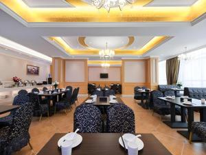 a restaurant with tables and chairs and a chandelier at Vienna Hotel Jiangxi Jiujiang Gongqingcheng High-Speed Railway Station in Gongqingcheng