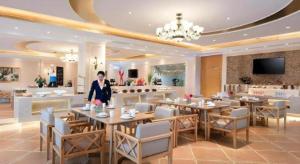 una mujer parada en un restaurante con mesas y sillas en Vienna Hotel Shanxi Datong High-Speed Railway Station Wanda Plaza, en Shuiposhi