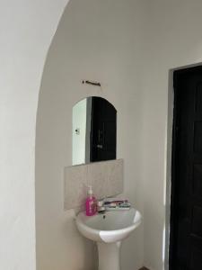 Un baño blanco con lavabo y espejo. en Raine house, en Ukunda