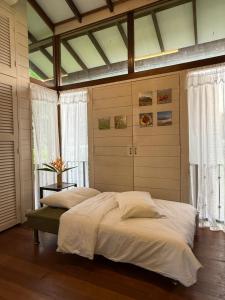 a bedroom with a large bed with white sheets at Rain Tree Country Home in Bukit Mertajam