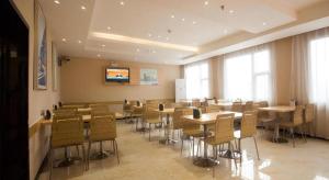 uma sala de jantar com mesas e cadeiras e uma televisão em City Comfort Inn Yichang Wanda Plaza Yunhe Park em Yichang