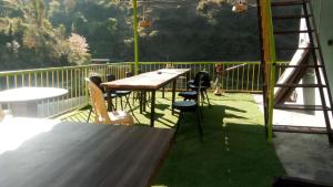 a table and chairs sitting on a deck with a table and a ladder at River Side Gorilla Resort Mussoorie in Mussoorie