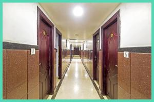 Un pasillo vacío con puertas marrones y un largo pasillo. en HOTEL Shiv P Near Shri Mahakaleshwar Jyotirlinga Temple - Railway Station Ujjain - Fully Air conditioned - Free Wifi and Parking Facilities, en Ujjain