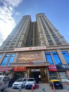 a tall building with cars parked in front of it at Borrman Hotel Korla Peacock River in Korla