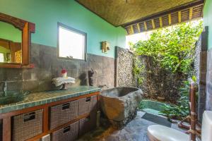 a bathroom with a bath tub and a sink at Kubu Tani in Sidemen