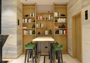a table with green chairs in a room with bookshelves at City Comfort Inn Wuhan Optics Valley OuYada Yangjiawan Metro Station in Wuhan