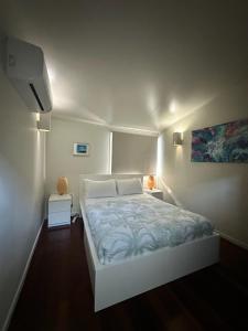 a white bedroom with a bed and a night stand at Allure Stradbroke Resort in Point Lookout