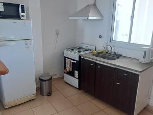 a kitchen with a stove and a sink and a refrigerator at Sol y Malbec Departamentos in Guaymallen