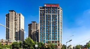 a tall building with a clock on the top of it at GreenTree Inn Express Kunming East Passenger Station Huazhicheng in Kunming