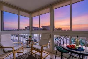 a balcony with two chairs and a table and some windows at San Marco Gulf Beach Views 3rd Floor in Venice