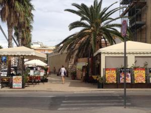 a person walking down a street with tables and umbrellas at Appartamento Francesca in Alghero