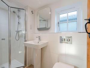 um banheiro branco com pia e chuveiro em 3 Bed in Stiffkey 85636 em Stiffkey mais 28 fotografias