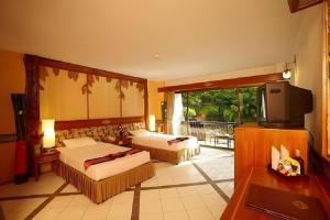 ein Hotelzimmer mit zwei Betten und einem Fernseher in der Unterkunft River Kwai Village Hotel in Ban Kaeng Raboet